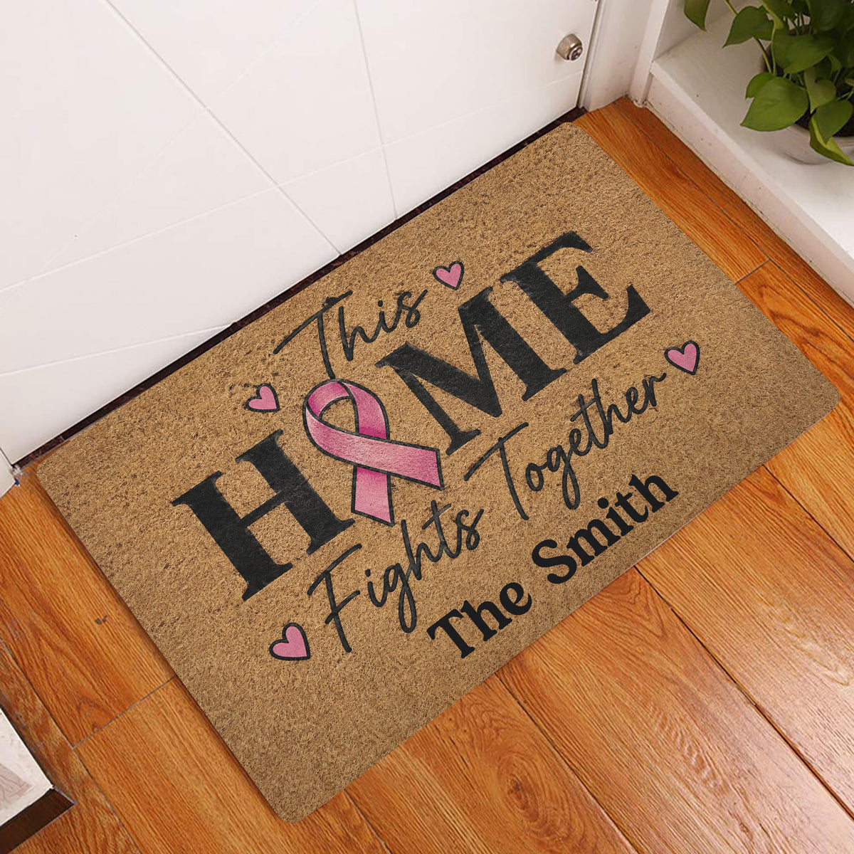 Breast cancer awareness doormat displayed at a home entrance on a wood floor
