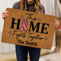 Person holding a breast cancer awareness doormat with pink ribbon and uplifting message
