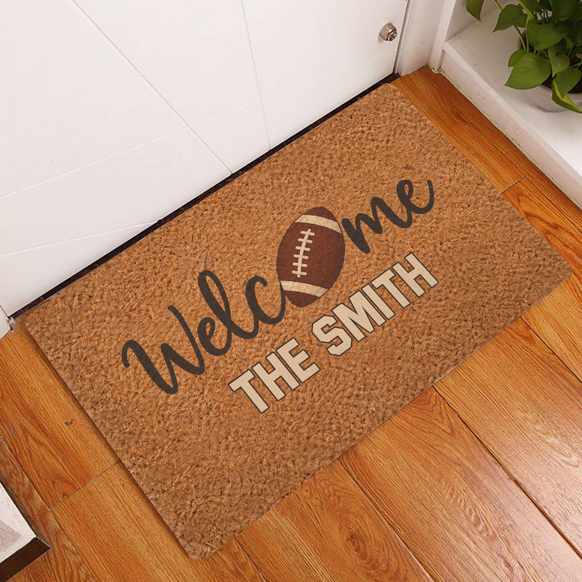 Football welcome doormat displayed at a home entrance beside a white door and wood flooring