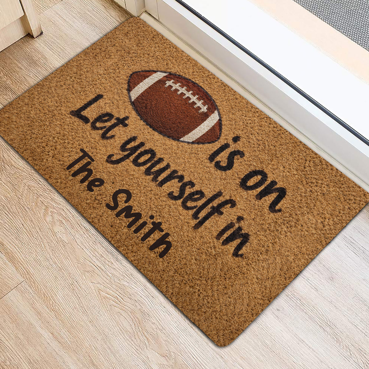 Football door mat styled at an interior entrance with a brown football graphic and welcoming message