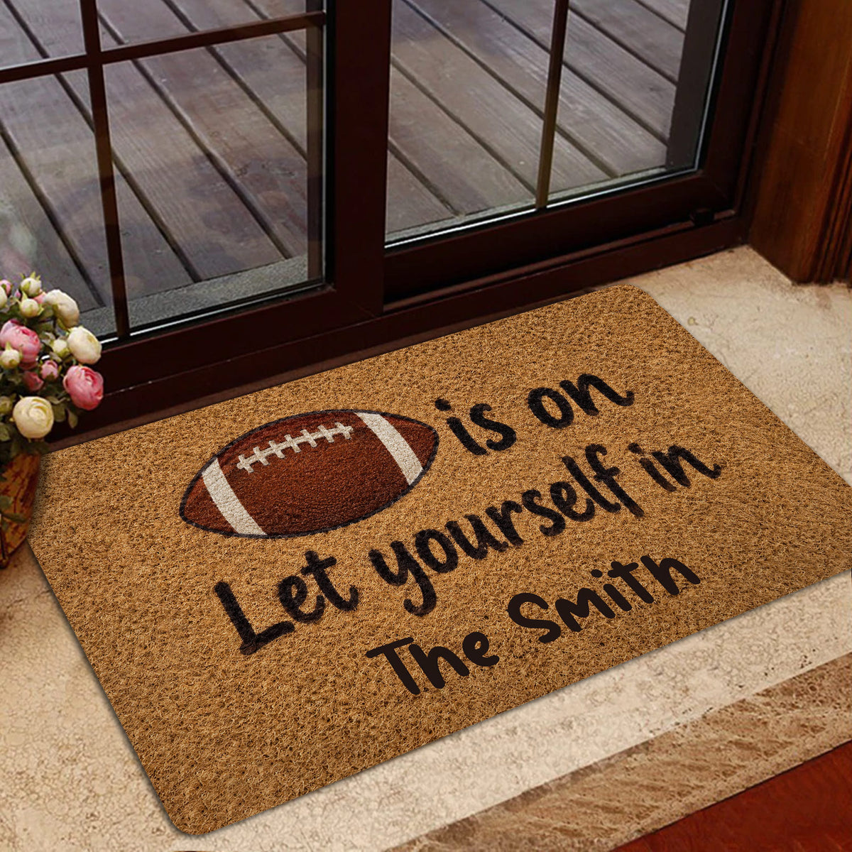 Football-themed entryway mat positioned near a glass door in a home entrance