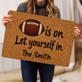 Person holding a football doormat featuring a classic football graphic and welcoming lettering