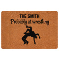 Wrestling-themed doormat with a black grappling silhouette and bold lettering on a warm brown surface