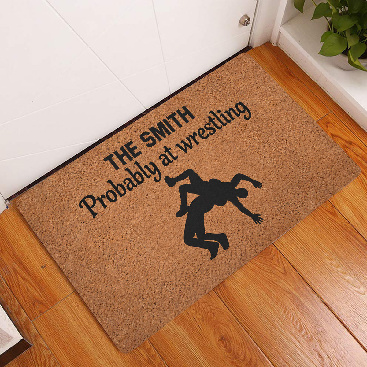 Wrestling doormat styled at an indoor entryway beside a white door and warm wood flooring