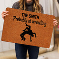 Person holding a wrestling-themed doormat featuring a bold black grappling silhouette