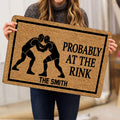 Wrestling doormat held indoors, featuring two grapplers in headgear and a bold black-and-tan design