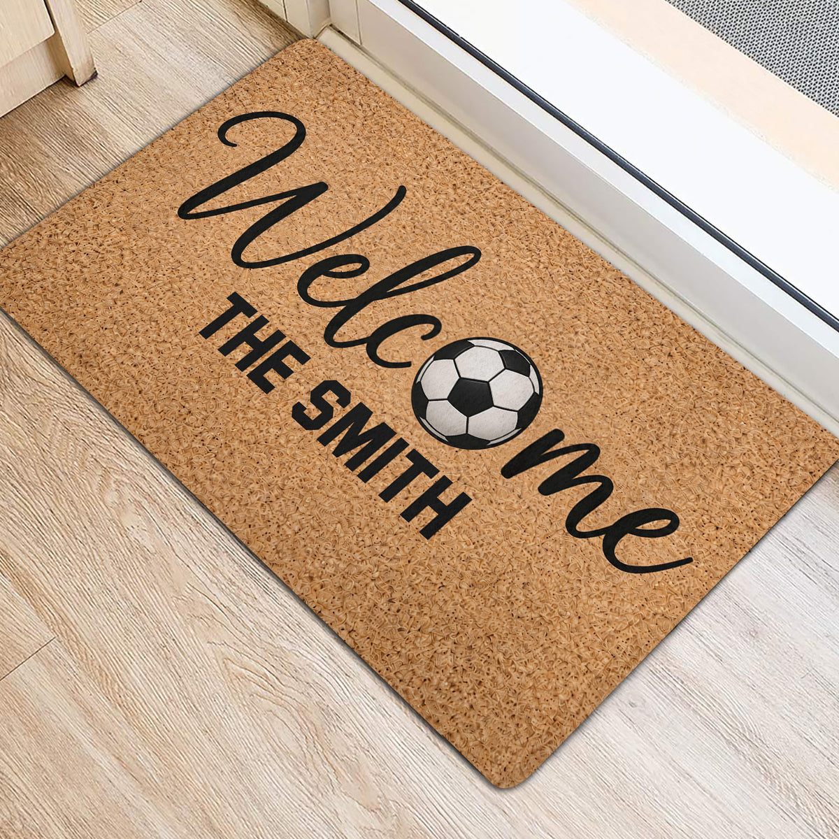 Soccer-themed door mat positioned near an entrance on light wood flooring