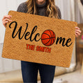 Person holding a basketball welcome doormat featuring an orange basketball and bold lettering