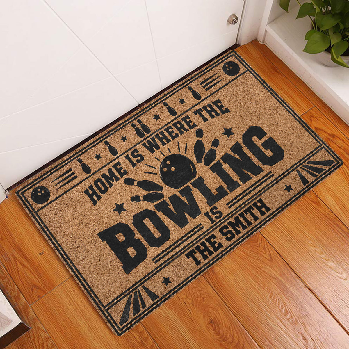 Bowling doormat displayed by an indoor door on hardwood flooring with bowling ball and pin artwork