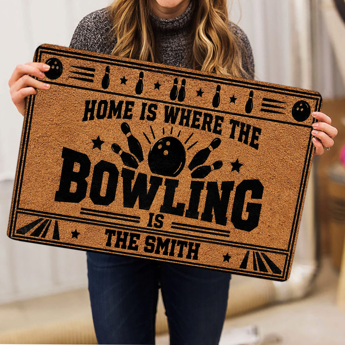 Bowling doormat held indoors, displaying bold black bowling artwork on a tan background