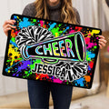 Cheerleading doormat held indoors, showing colorful paint splashes, pom-poms, and megaphone artwork
