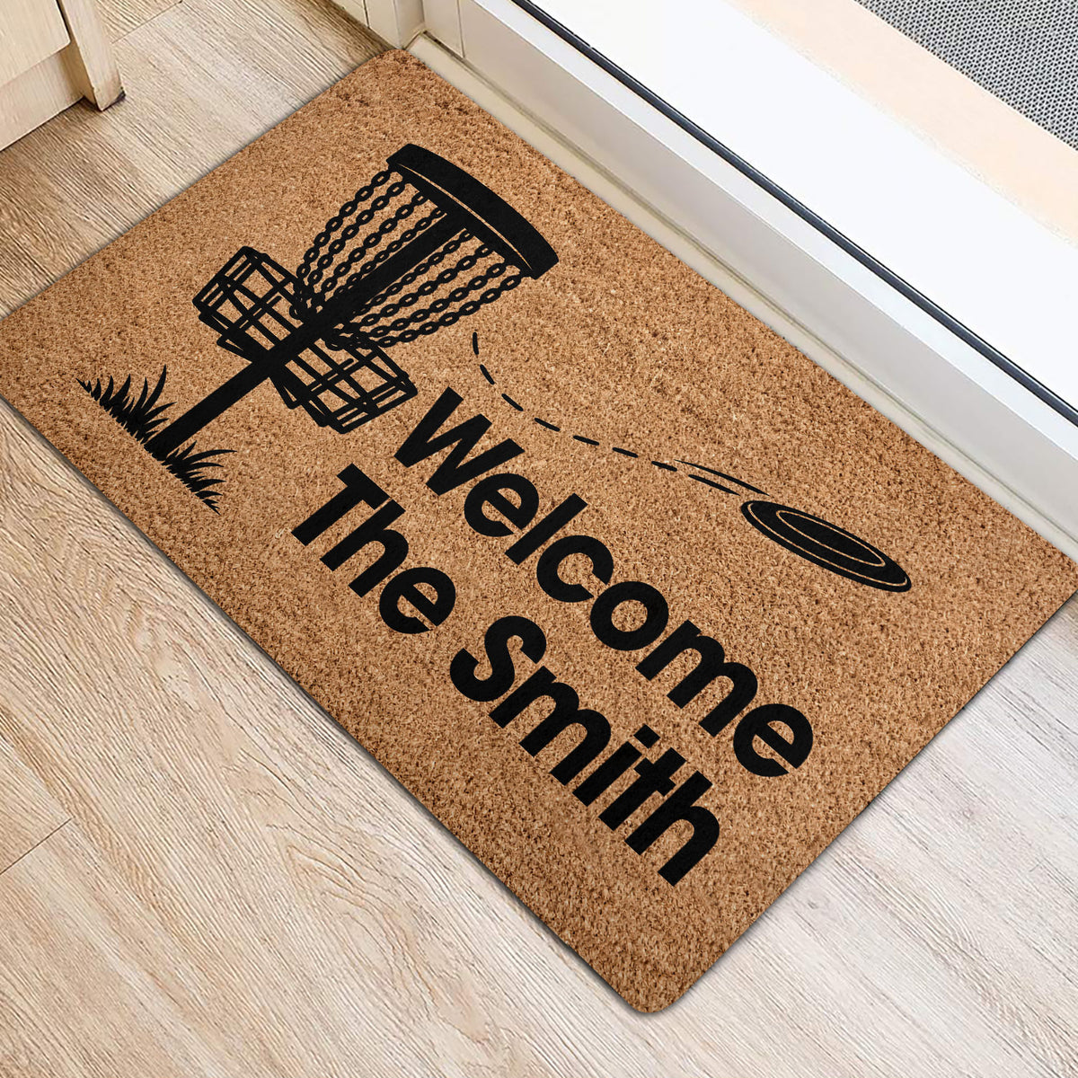 Disc golf door mat shown beside an entryway door with a basket, flying disc, and welcome artwork