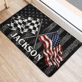 Racing flag doormat placed inside an entryway, featuring checkered and American flags on a distressed design