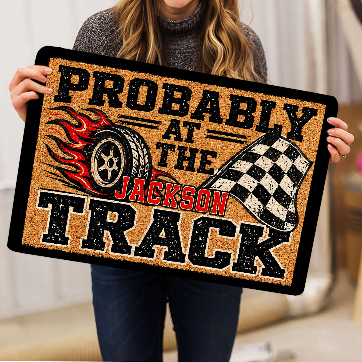 Dirt track racing doormat held indoors, featuring a flaming tire and checkered flag design