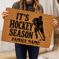 Hockey doormat held indoors, featuring a black ice hockey player silhouette and large seasonal lettering