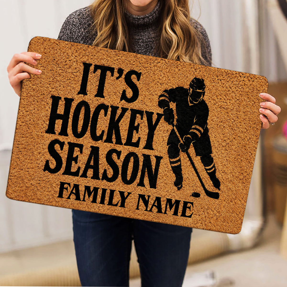 Hockey doormat held indoors, featuring a black ice hockey player silhouette and large seasonal lettering