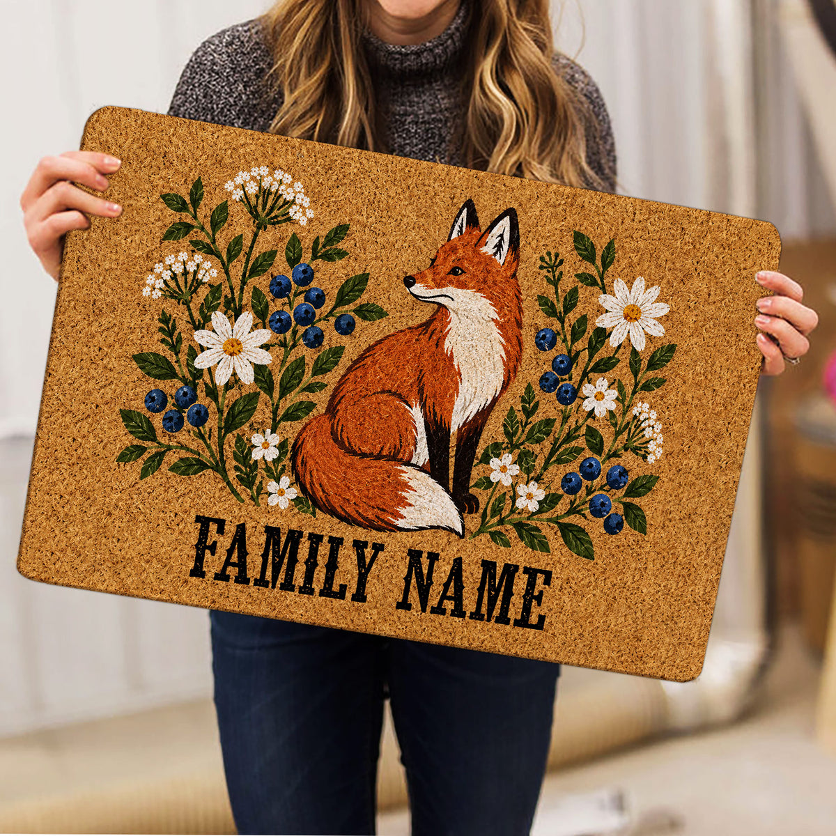Person holding a fox doormat featuring wildflowers, blueberries, and a rustic nature-inspired design