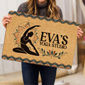Yoga studio doormat held indoors, showing a meditating figure, lotus motifs, and an earthy decorative border