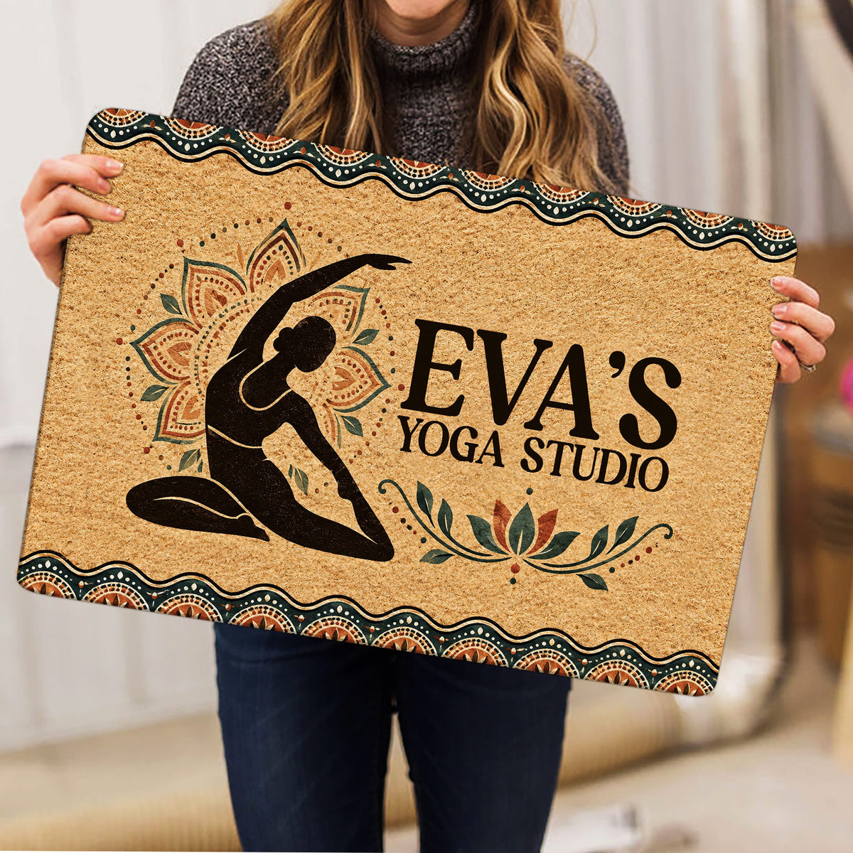 Yoga studio doormat held indoors, showing a meditating figure, lotus motifs, and an earthy decorative border