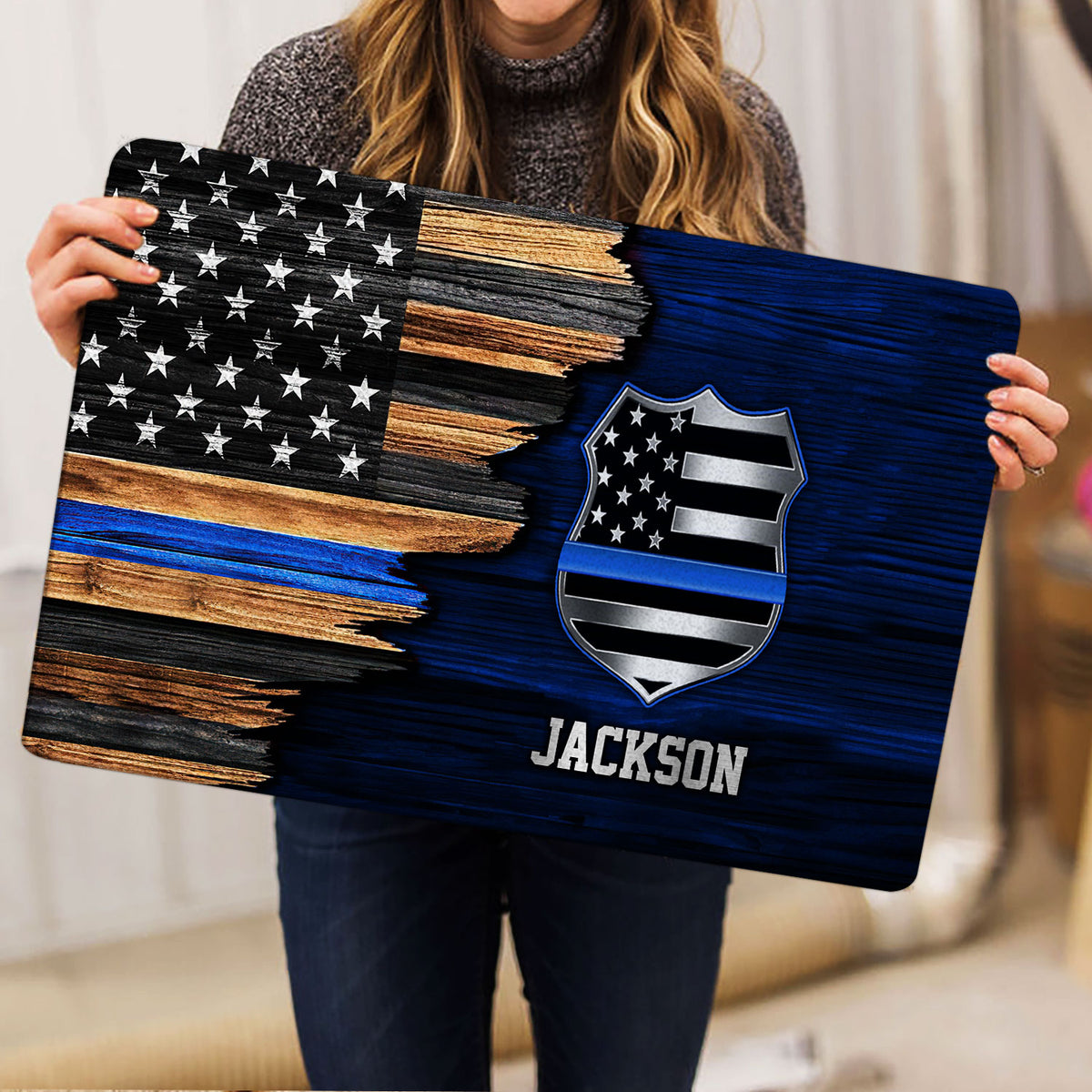Person holding a police badge doormat featuring distressed American flag artwork and blue accents