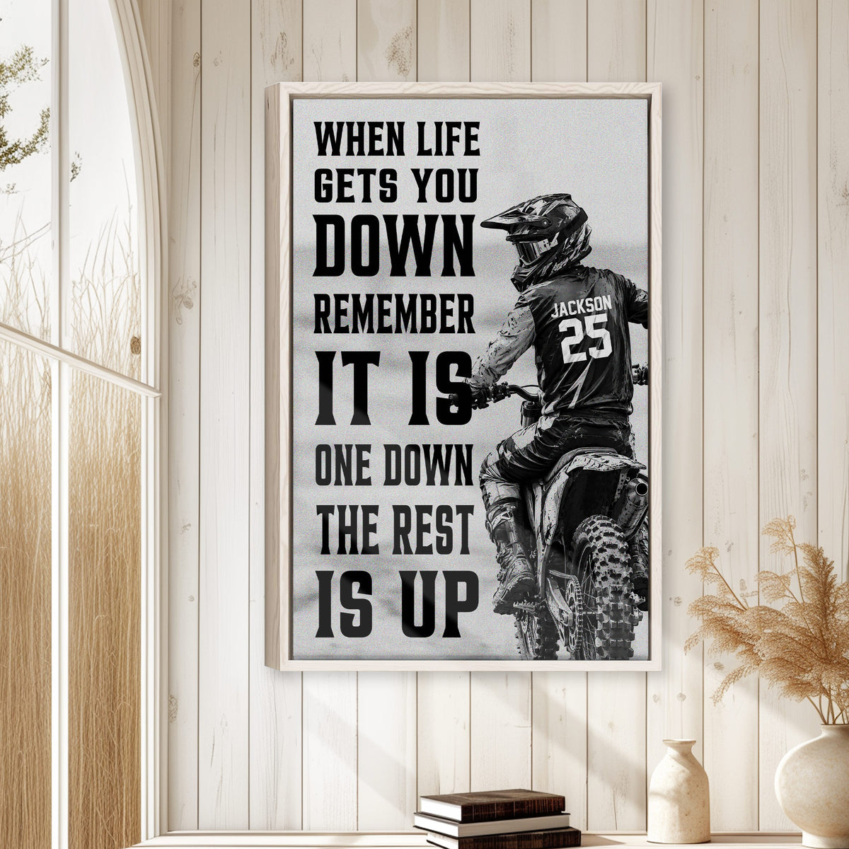 Motocross wall art displayed in a bright wood-paneled room above a small stack of books