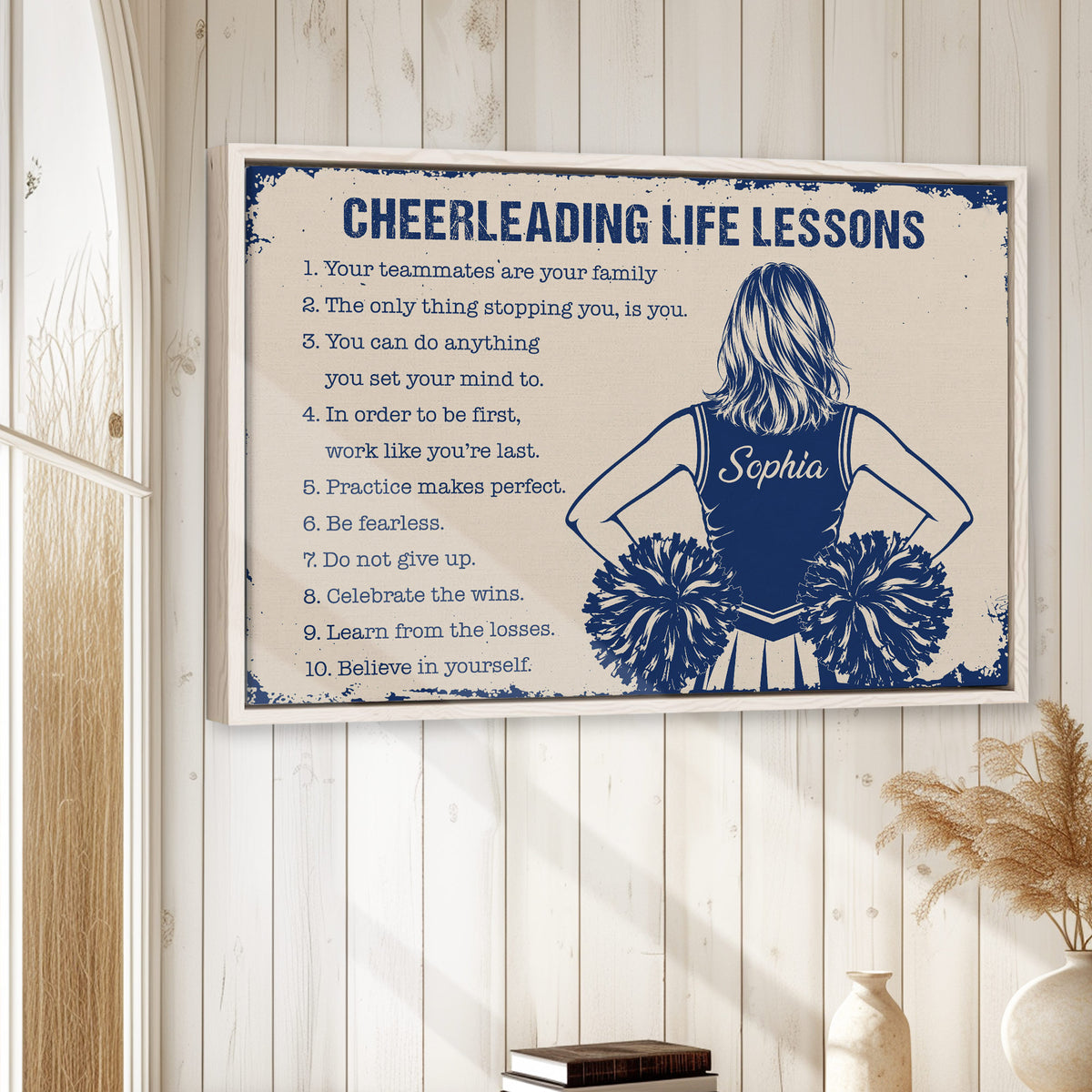 Framed cheerleading wall art displayed on a light wood-paneled wall in a home setting