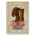 Framed cowboy wall art featuring a brown western hat and boots with pink flowers over vintage dictionary pages