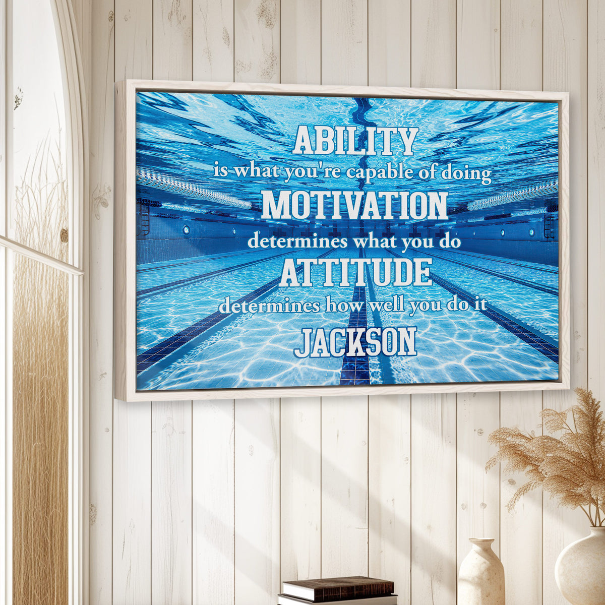 Swimming wall art displayed in a bright home interior above books and neutral decor