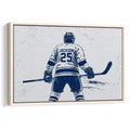Framed hockey wall art featuring a player with a stick in a navy blue and white illustrated design