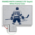 White framed canvas hockey wall art with a navy and white player illustration and close-up canvas detail