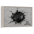 Framed hockey wall art featuring a black puck breaking through a cracked gray surface