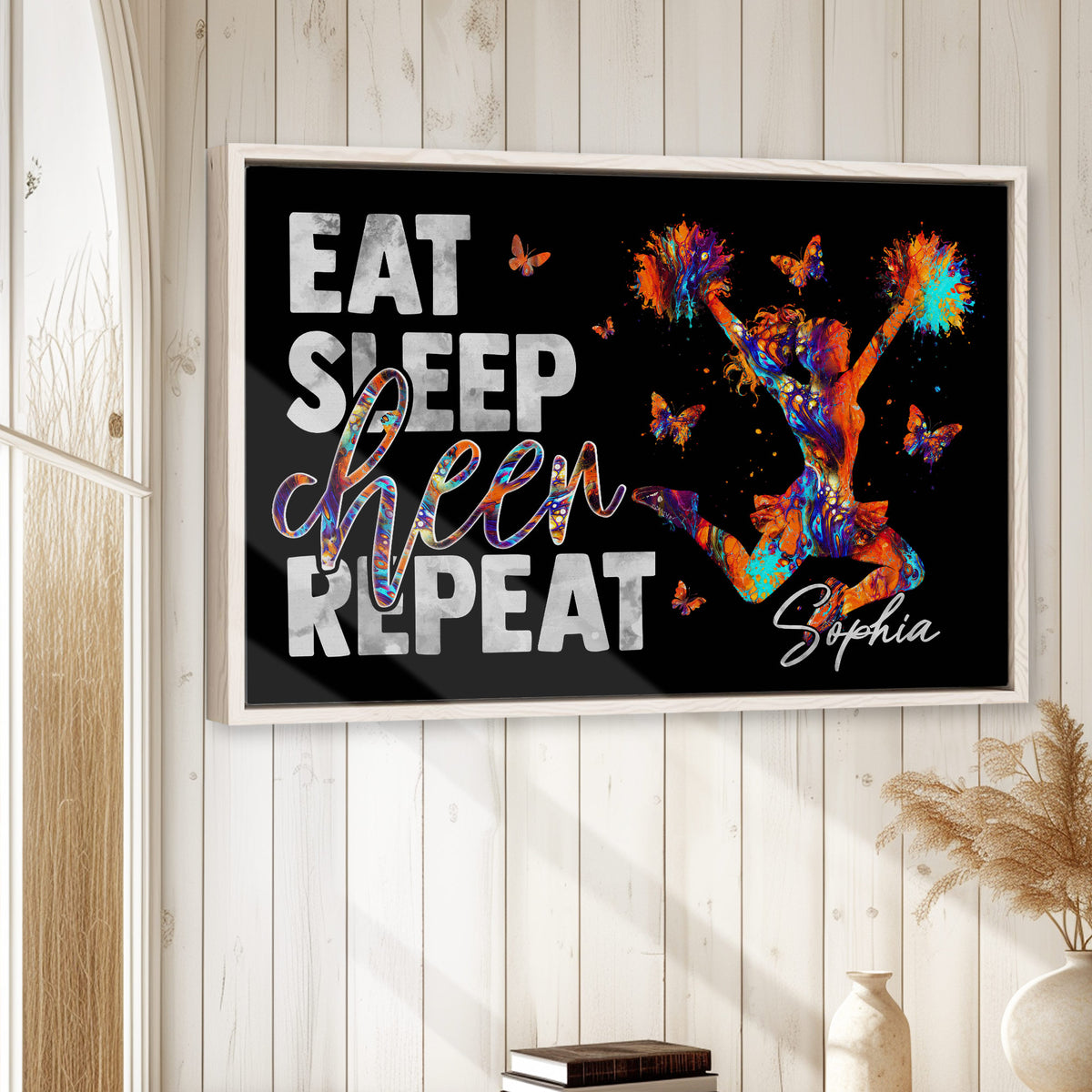 Framed cheerleading wall art displayed on a light wood paneled wall in a bright home setting