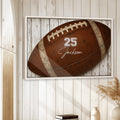 Framed football wall art displayed on a bright white wood wall in a relaxed home setting
