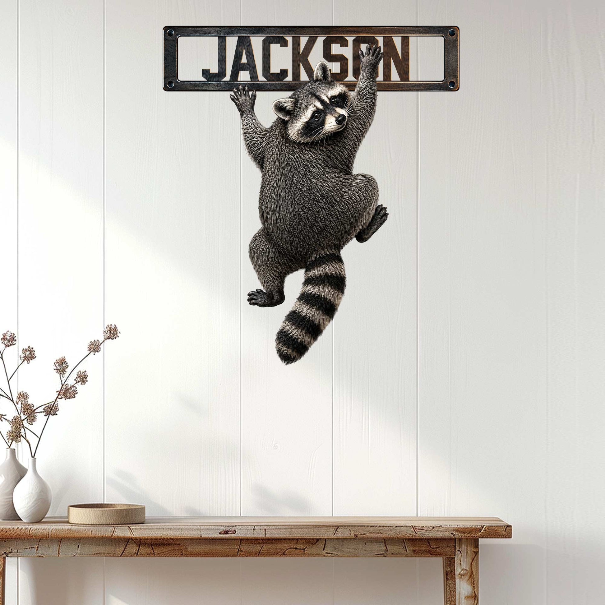 Climbing raccoon metal sign displayed on a white paneled wall above a wooden console table