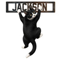 Tuxedo cat metal sign featuring a playful black-and-white cat holding onto a rustic sign frame