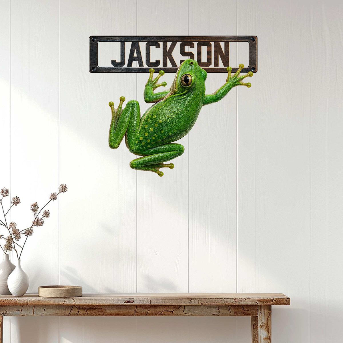 Green frog metal wall sign displayed on a bright white paneled wall in a home entryway