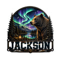 Custom bear metal sign featuring a wilderness lake, mountain forest, campfire, and colorful northern lights