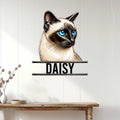 Siamese cat metal wall sign displayed on a light wood-paneled wall above a console table