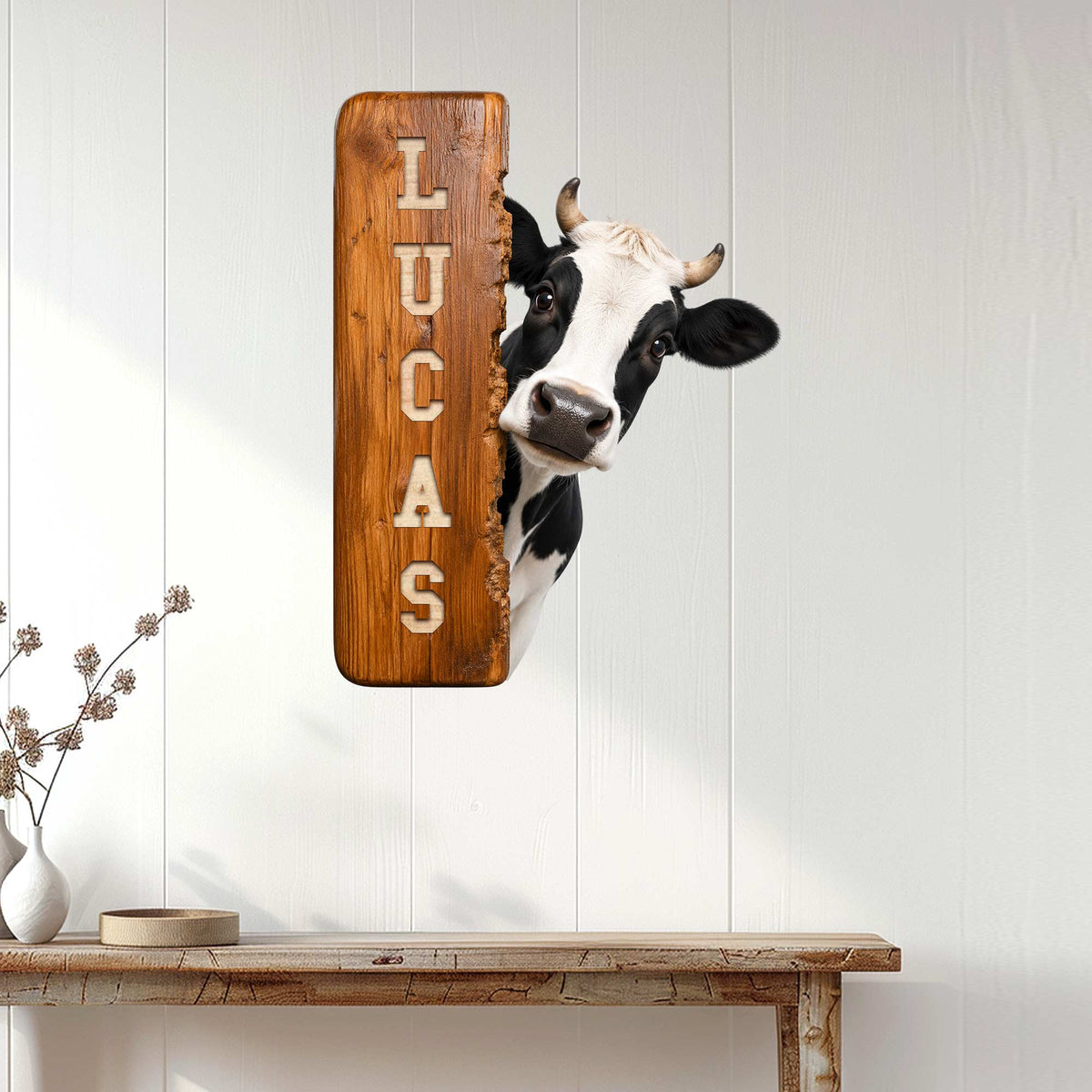 Rustic cow metal wall sign displayed on a white paneled wall above a console table