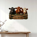 Rustic three-cow metal wall sign displayed on a light wood-paneled wall above a console table