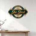 Decorative She Shed metal sign displayed on a light paneled wall above a rustic console table