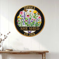 Floral She Shed metal sign displayed on a light wall above a rustic console table