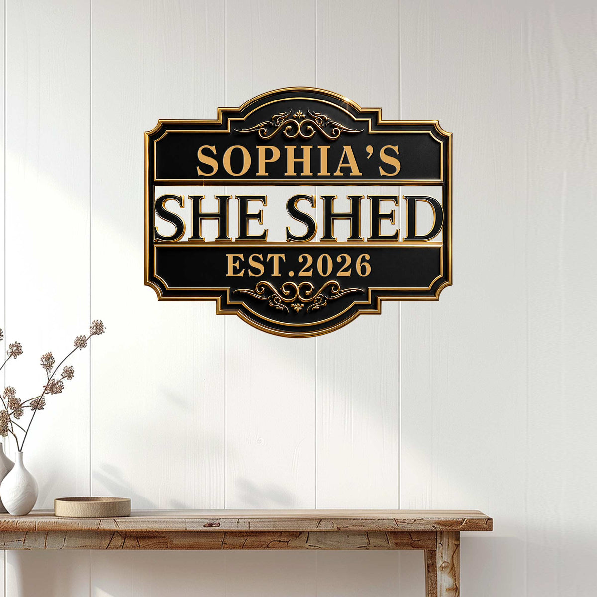 Black and gold She Shed wall sign displayed on white paneling above a rustic console table
