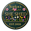 Round custom She Shed metal sign with gold accents, colorful flowers, and elegant garden-inspired artwork
