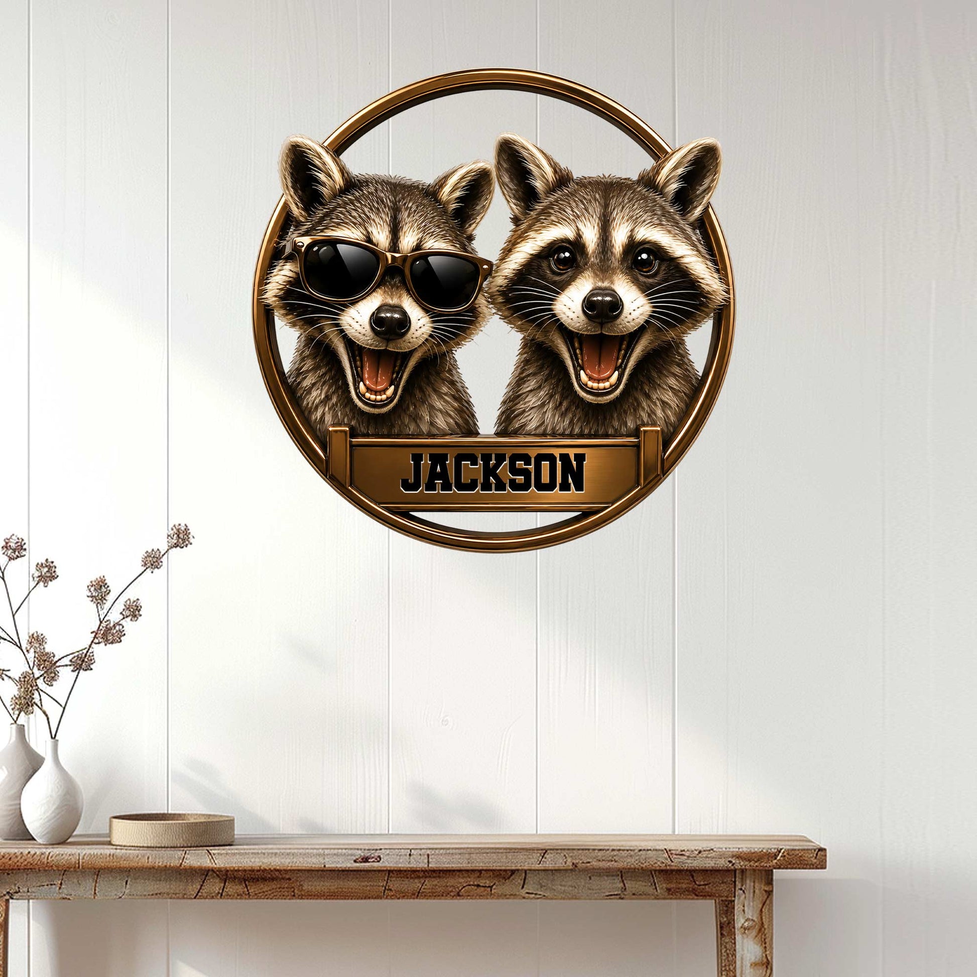 Two-raccoon metal wall sign displayed on a light wood-paneled wall in a home entryway