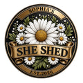 Floral She Shed metal sign featuring a large white daisy, smaller blooms, leafy greenery, and a gold banner