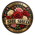 Round She Shed metal sign with rich red, pink, and cream roses in a decorative gold and black crest