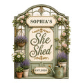 Ornate custom She Shed metal sign framed by roses, lavender, daisies, potted plants, and garden details