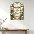 Floral She Shed metal sign displayed on a white paneled wall in a bright home interior