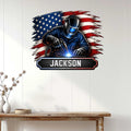 Welder wall sign displayed on a white paneled wall above a rustic console table